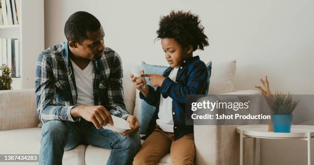 father teaching energy saving to his son. - energy efficient lightbulb 個照片及圖片檔