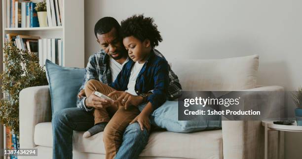 father teaching energy saving to his son. air condition temperature. - air conditioner family stock pictures, royalty-free photos & images