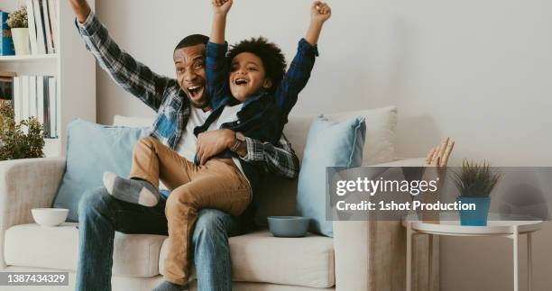 father and son watching tv at home. cheering. - kid cheering stock pictures, royalty-free photos & images