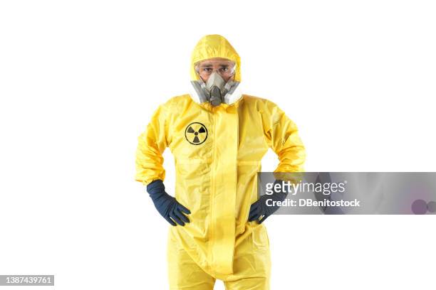 technician in yellow nuclear protection suit, mask and goggles, posing with arms akimbo, on white background. concept of nuclear energy and pandemics. - weapons of mass destruction stock pictures, royalty-free photos & images
