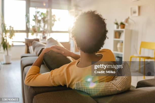 rear view of woman sitting on the couch - back of sofa stock pictures, royalty-free photos & images