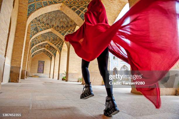 woman in red cloak running traditional iranian style courtyard - iran street stock pictures, royalty-free photos & images