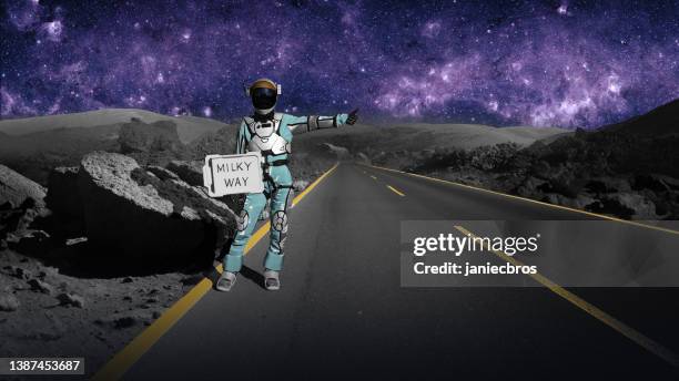astronauta haciendo autostop en el espacio sosteniendo el letrero de la "vía láctea". volver a casa - hitchhiking fotografías e imágenes de stock