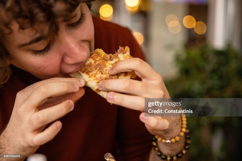 Boy eating a wrap sandwich with hands