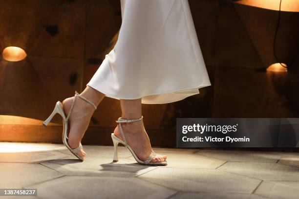 low angle view of woman in high heels and white dress walking. - womens beautiful feet stock-fotos und bilder
