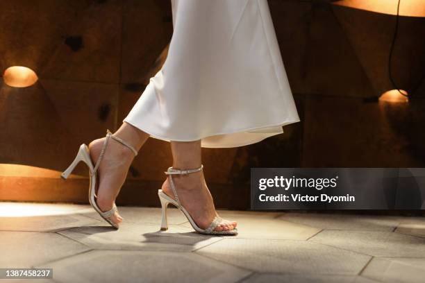 low angle view of woman in high heels and white dress walking. - human foot stockfoto's en -beelden