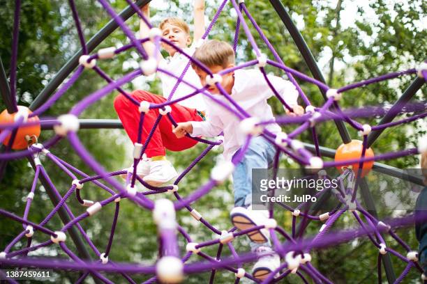 vorschulkinder genießen auf dem spielplatz - kinder klettern stock-fotos und bilder
