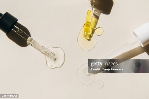 pipettes with drops of cosmetic liquid on beige background. beauty product with peptides, ceramides, hyaluronic gel, polyglutamic acid, essential oil, cbd, retinol, collagen. multitasking beauty. flat lay, top view. - jojoba stock pictures, royalty-free photos & images