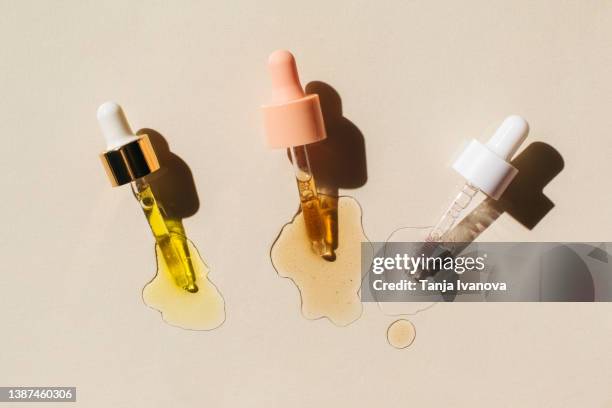 pipettes with drops of cosmetic liquid on beige background. beauty product with peptides, ceramides, hyaluronic gel, polyglutamic acid, essential oil, cbd, retinol, collagen. multitasking beauty. flat lay, top view. - serum stock pictures, royalty-free photos & images