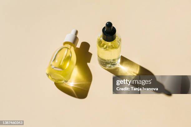 glass bottles with cosmetic liquids on beige background. cosmetic product with peptides, ceramides, hyaluronic gel, polyglutamic acid, essential oil, cbd, retinol, collagen. multitasking beauty. flat lay, top view - bottles glass top stock pictures, royalty-free photos & images