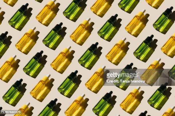 pattern of glass bottles with cosmetic liquids on beige background. cosmetic product with peptides, ceramides, hyaluronic gel, polyglutamic acid, essential oil, cbd, retinol, collagen. multitasking beauty. flat lay, top view - bottles glass top stockfoto's en -beelden