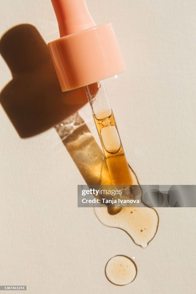 Liquid gel or serum drop with pipette on beige background. Beauty product with peptides, ceramides, hyaluron gel, polyglutamic acid. Multitasking beauty. Flat lay, top view.