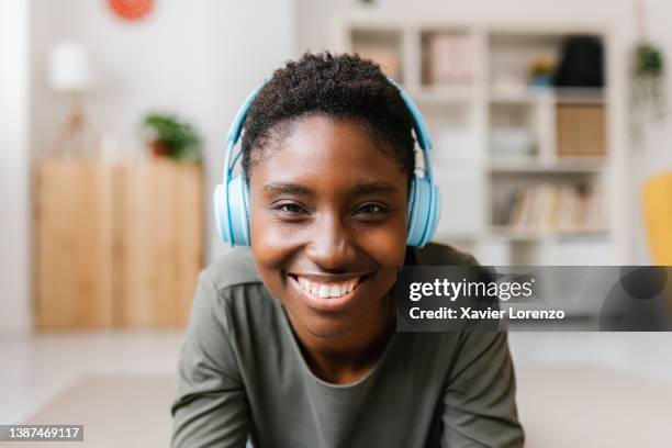 screen view of african american woman in headphones looking at camera and smiling while having a video conference at home. - videollamada fotografías e imágenes de stock