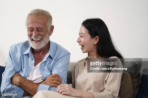 happy family elderly father laughing with daughter while sitting on sofa at home - tears of joy stock-fotos und bilder