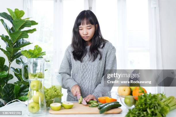 young woman preparing vegetable and fruit for making vegetable juice healthy drinking - raw food diet stockfoto's en -beelden
