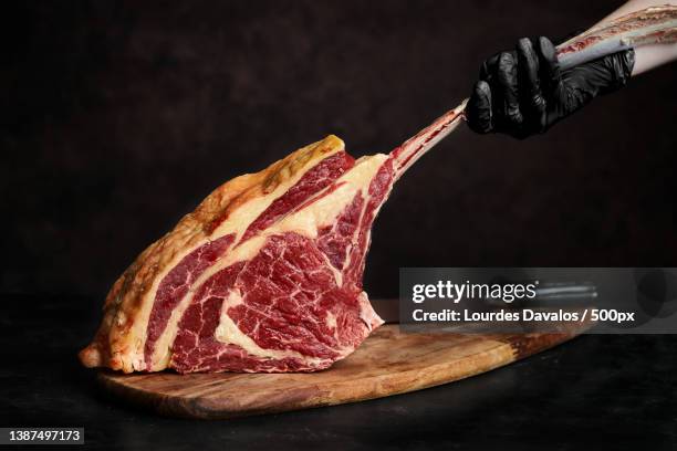 close-up of meat on cutting board over black background - tomahawk stock pictures, royalty-free photos & images