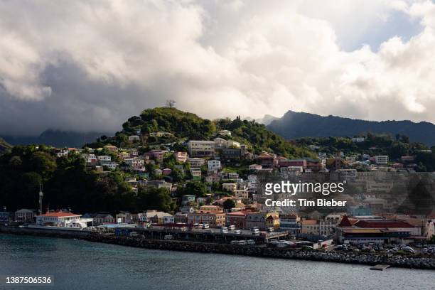 colorful buildings dot the hilly coastline in saint george, grenada, an island in the caribbean sea - grenada invasion fotografías e imágenes de stock