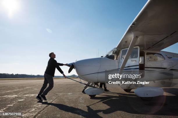 pilot pushing airplane into position on runway - private aeroplane stock pictures, royalty-free photos & images