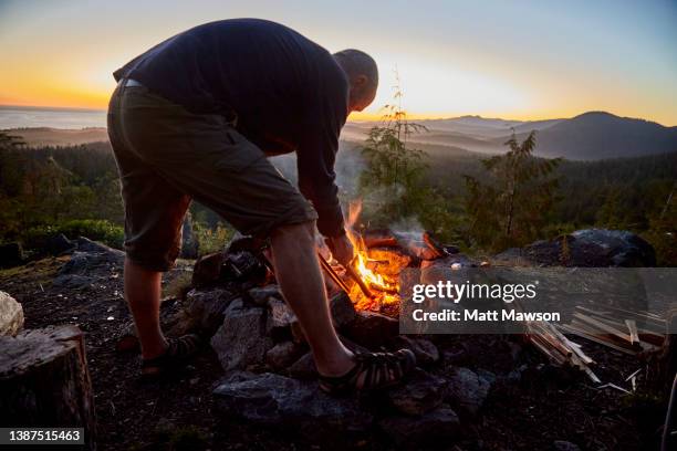 a senior man and his campfire vancouver island bc canada - brennholz stock-fotos und bilder