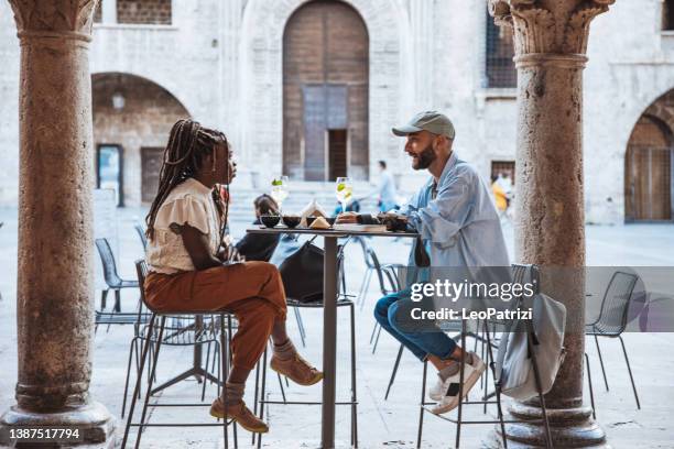 couple of tourists sitting in a cafe taking an aperitif at the happy hour - italy city break stock pictures, royalty-free photos & images