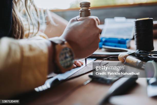 unrecognizable woman using her tools to artistically imprint patterns onto leather in her design studio and workspace. leather craftswoman. independent small business. workers' day. marroquinery. - may day international workers day 個照片及圖片檔