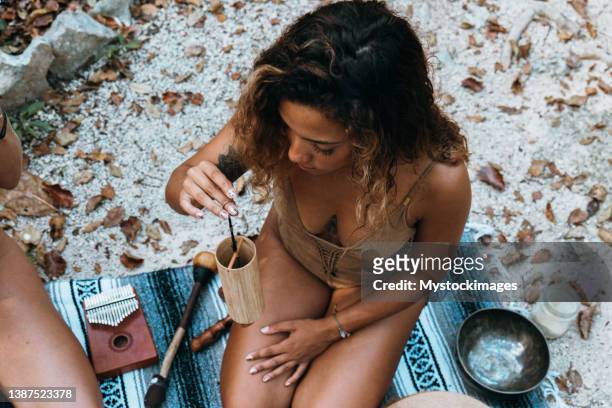 one multiracial woman practicing sound healing ceremony in the rainforest - tambourine stock pictures, royalty-free photos & images