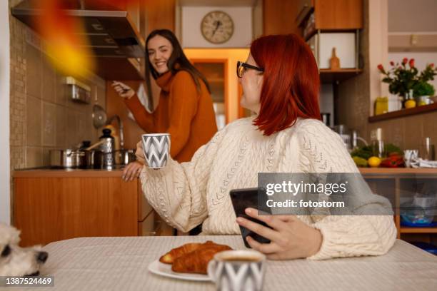 woman enjoying coffee and looking over shoulder at her daughter that is cooking lunch - dog looking over shoulder stock pictures, royalty-free photos & images