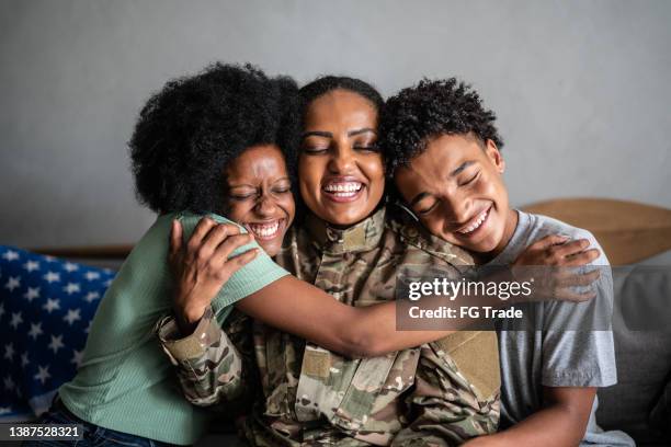 soldier mother embracing son and daughter at home - military veteran armed forces stock pictures, royalty-free photos & images