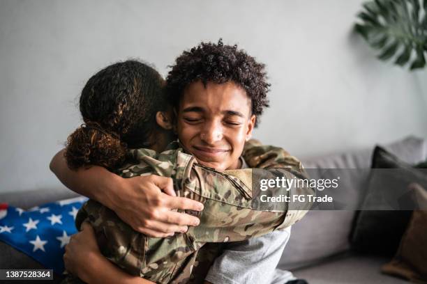 la mère et le fils du soldat s’étreignent à la maison - armée américaine photos et images de collection