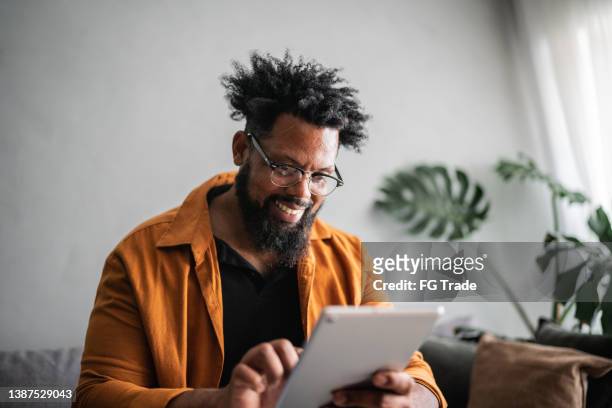 mature man using digital tablet at home - ereader stockfoto's en -beelden
