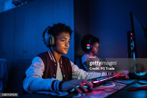 teenage boy playing on the computer at home - gamers stockfoto's en -beelden