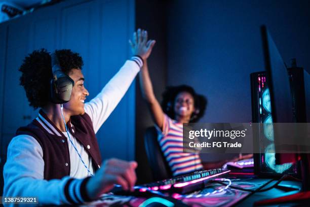 friends doing a high five while playing on the computer at home - world showdown of esports stockfoto's en -beelden