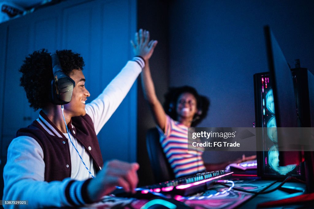 Friends doing a high five while playing on the computer at home