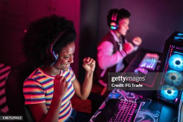 young woman celebrating while playing on the computer at home - massively multiplayer online game stock pictures, royalty-free photos & images