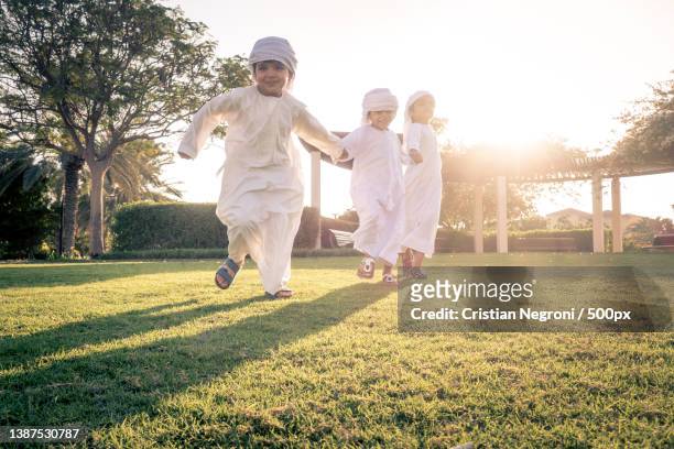 children playing together in traditional clothing playing on field - uae heritage stock pictures, royalty-free photos & images