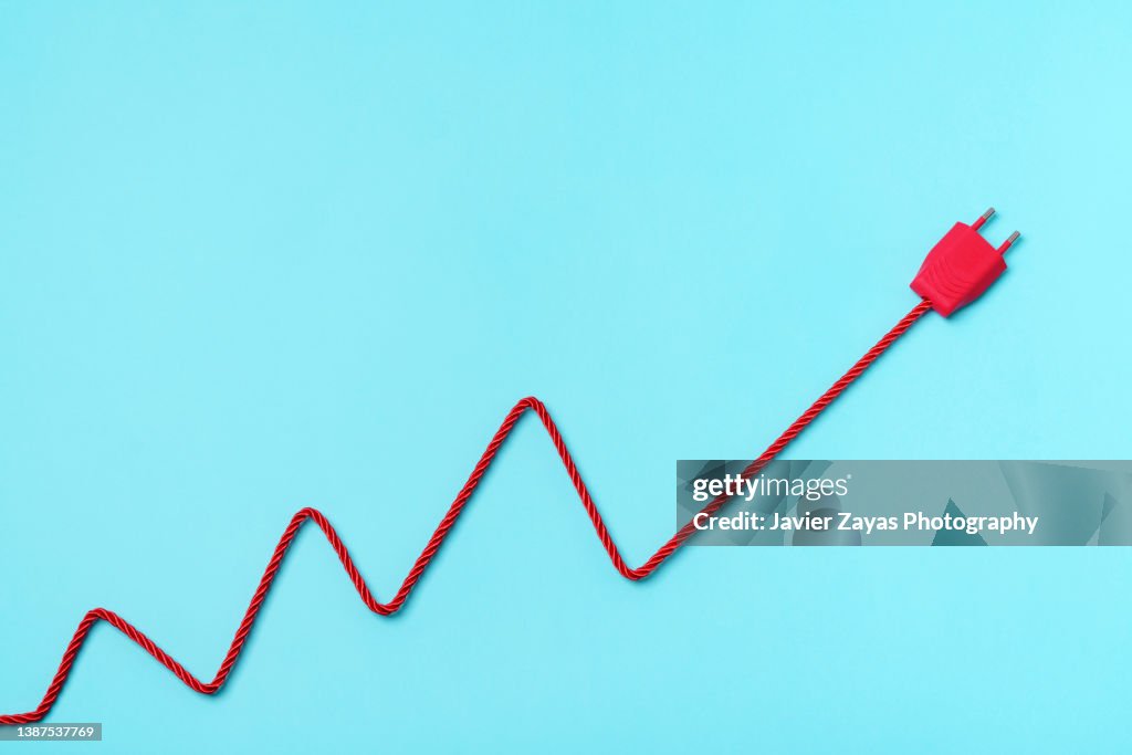 Red Electric Power Plug On Blue Background. Increase To Electricity Prices Concept.