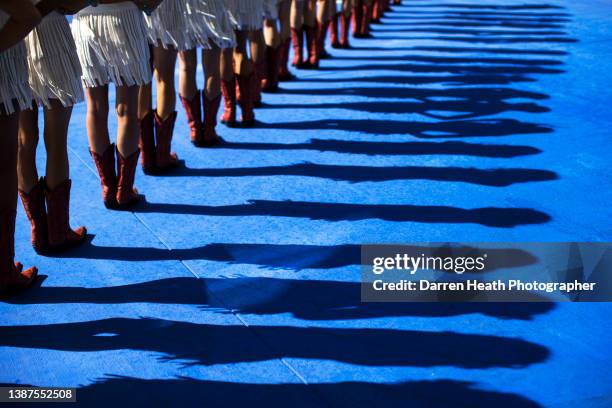 The shadows thrown by cowgirl outfit and cowboy boots wearing grid girls standing in a line in the pit lane during the Formula One drivers' parade at...