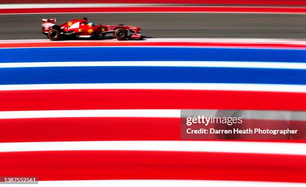 Spanish Scuderia Ferrari Formula One racing team racing driver Fernando Alonso driving his F138 racing car at speed alongside red, white and blue...