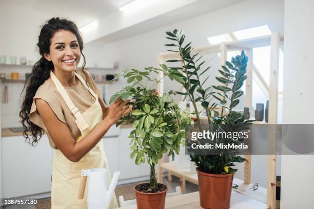young woman enjoying with her plants at home - apron stock pictures, royalty-free photos & images