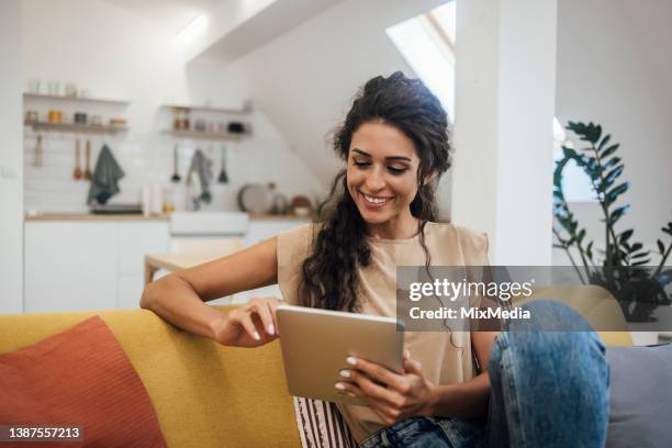 portrait of a happy young woman using tablet at home - happy ipad beautiful stockfoto's en -beelden