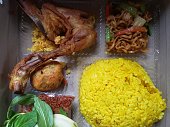 Yellow rice uduk with side dishes of fried chicken, cakes, tempeh oreg, and chili sauce, is a typical Indonesian Javanese dish.