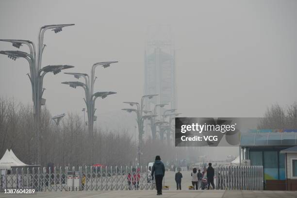 People walk at the Olympic Park during a smoggy day on March 24, 2022 in Beijing, China.