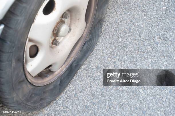 flat tyre in the street of a car parked in the street. - felge stock-fotos und bilder