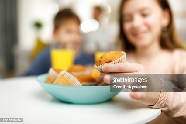 primer plano de una chica comiendo magdalenas en casa. - cupcakes girls fotografías e imágenes de stock