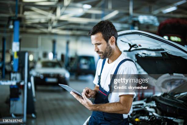 riparatore automatico che lavora su tablet digitale in officina. - auto garage foto e immagini stock