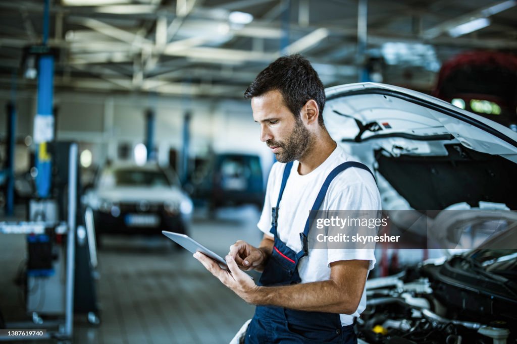 Auto repairman working on digital tablet in a workshop.