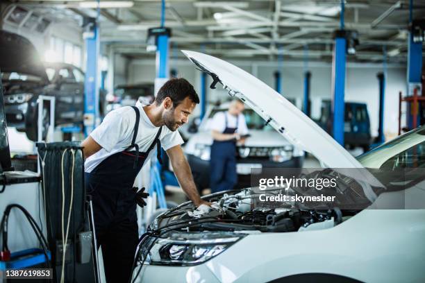 automechaniker, der motorprobleme während der arbeit in einer werkstatt analysiert. - car servicing stock-fotos und bilder