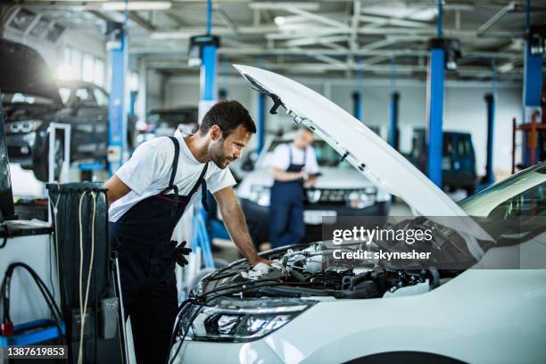 auto mechanic analyzing engine problems while working in a workshop. - autogarage stockfoto's en -beelden