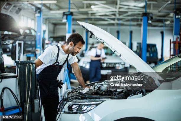 auto mechanic analyzing engine problems while working in a workshop. - car maintenance stockfoto's en -beelden