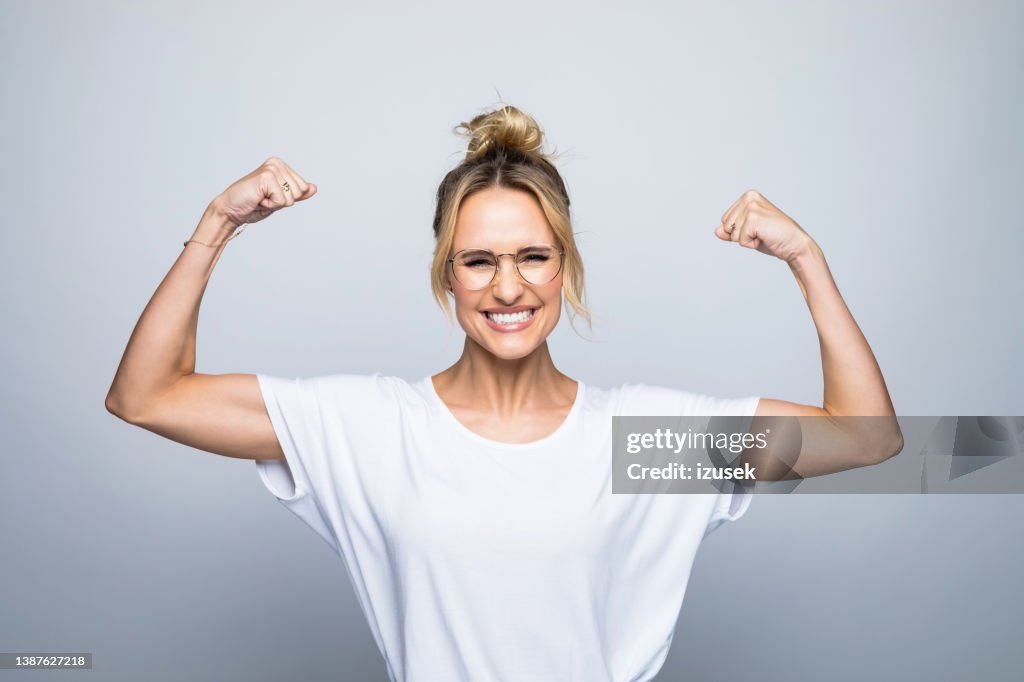 Portrait of happy beautiful woman flexing muscle